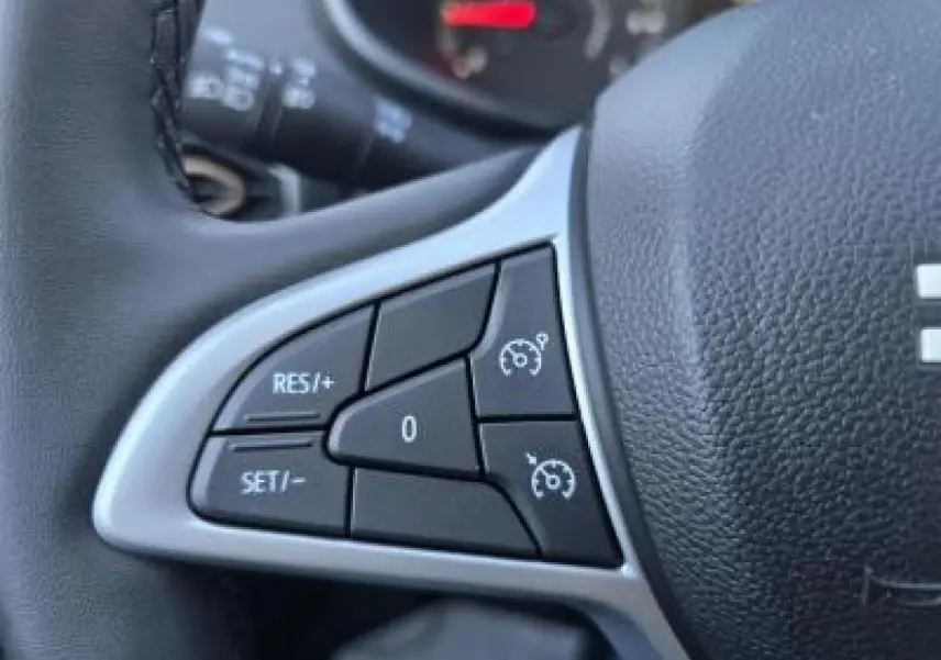 Gros plan sur les commandes du régulateur de vitesse au volant noir du Dacia Sandero III Stepway 2025.