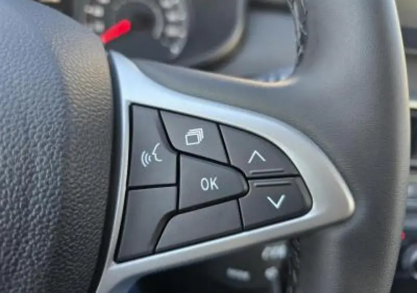 Gros plan sur les commandes au volant noir Soft Feel du Dacia Sandero III Stepway 2025 avec bouton OK et flèches directionnelles.