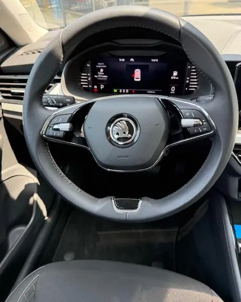 Vue intérieure centrée sur le volant cuir noir et le tableau de bord numérique du Skoda Kamiq 2024.