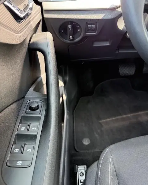 Détail intérieur côté conducteur du Skoda Kamiq noir 2024, montrant les commandes des vitres et l'interrupteur des phares.