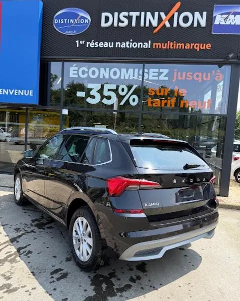 Vue 3/4 arrière droite d'un Skoda Kamiq noir 2024 garé devant une vitrine avec enseigne Distinxion.