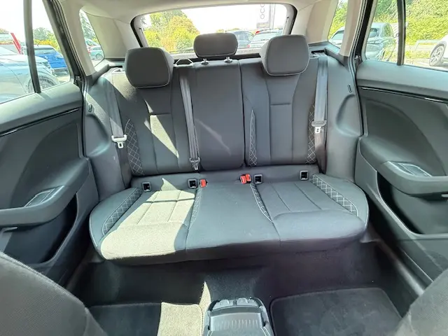 Vue arrière intérieure du Skoda Kamiq noir 2024, montrant la banquette arrière en tissu avec ceintures et appuie-têtes.