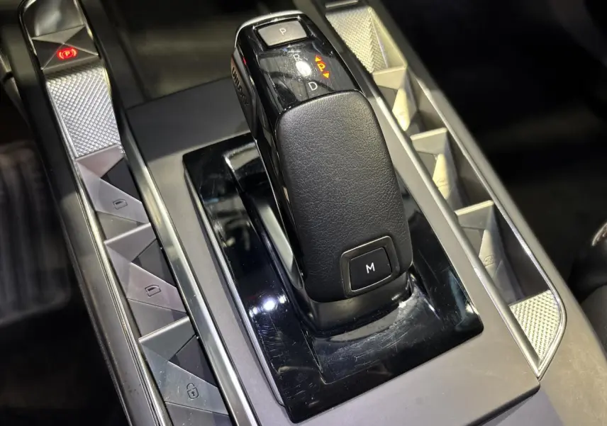 Gros plan sur la commande de boîte automatique noire du DS3 Crossback 2024, avec boutons de contrôle et finitions argentées.