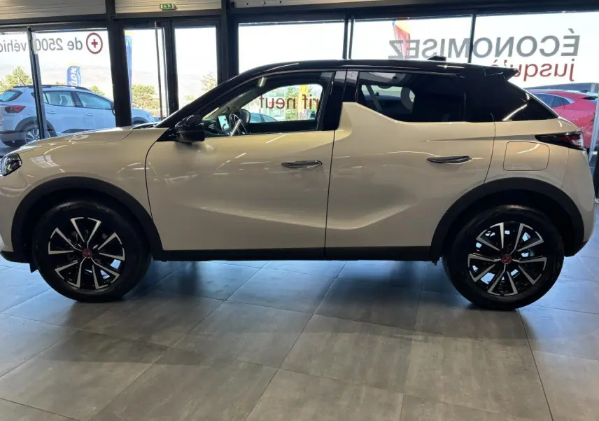 Vue de profil côté gauche du DS3 Crossback 2024 en couleur Crystal Pearl avec toit noir et jantes noires distinctives.