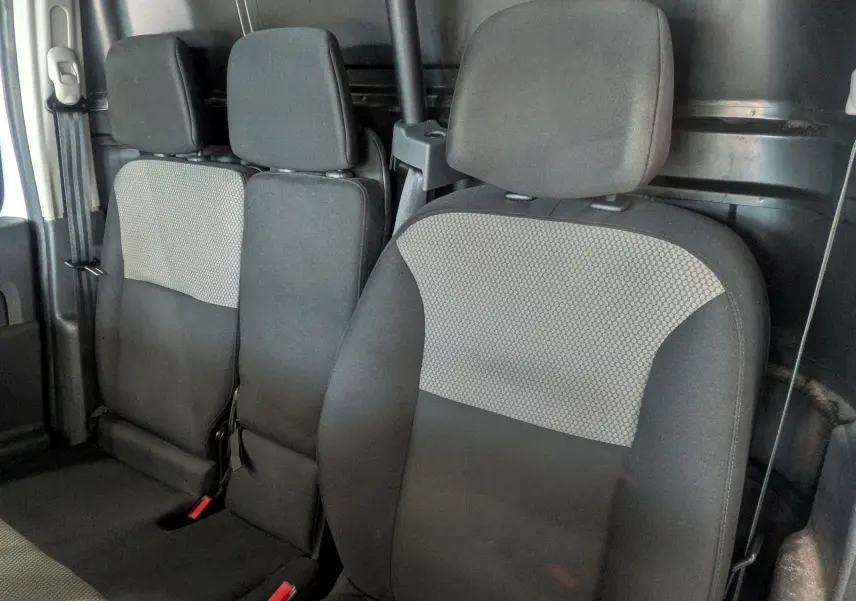 Vue intérieure des sièges avant et arrière en tissu gris et noir du Renault Kangoo Express blanc, version Blue dCi 95 CH Extra.
