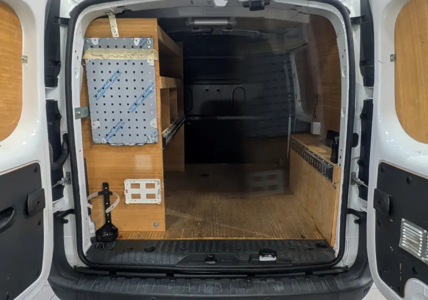 Vue arrière ouverte du Renault Kangoo Express blanc minéral, montrant l'aménagement boisé intérieur utilitaire.