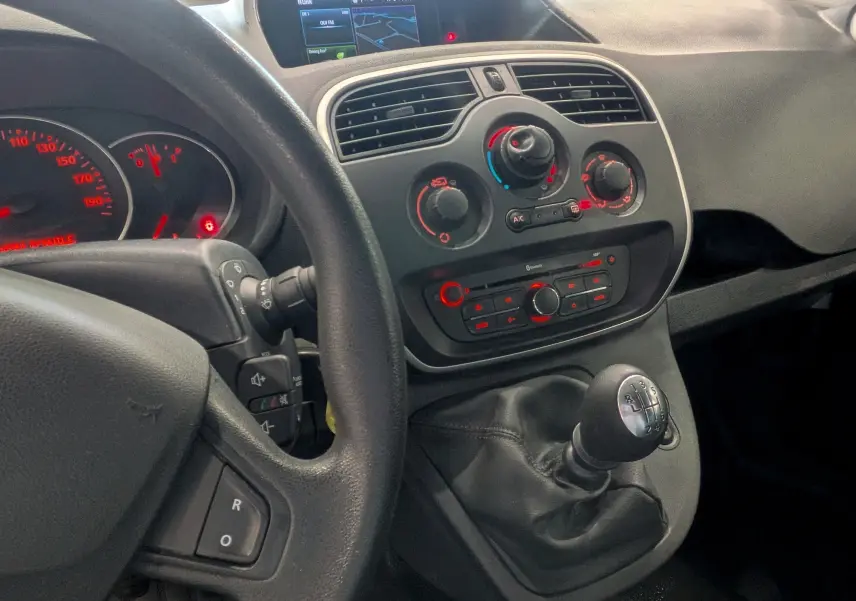 Vue intérieure centrée sur la console centrale et levier de vitesses manuelle du Renault Kangoo Express 2020, tableau de bord visible.