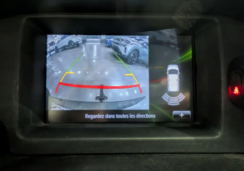 Écran de caméra de recul du Renault Kangoo Express blanc, affichant les lignes de guidage et l'alerte de proximité arrière.
