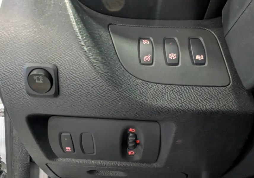 Gros plan sur les commandes intérieures noires du tableau de bord côté gauche du Renault Kangoo Express blanc.