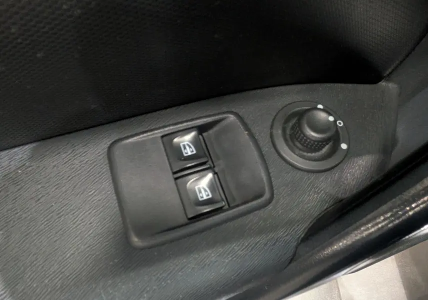 Gros plan sur les commandes de lève-vitres et réglage des rétroviseurs côté conducteur du Renault Kangoo Express blanc.