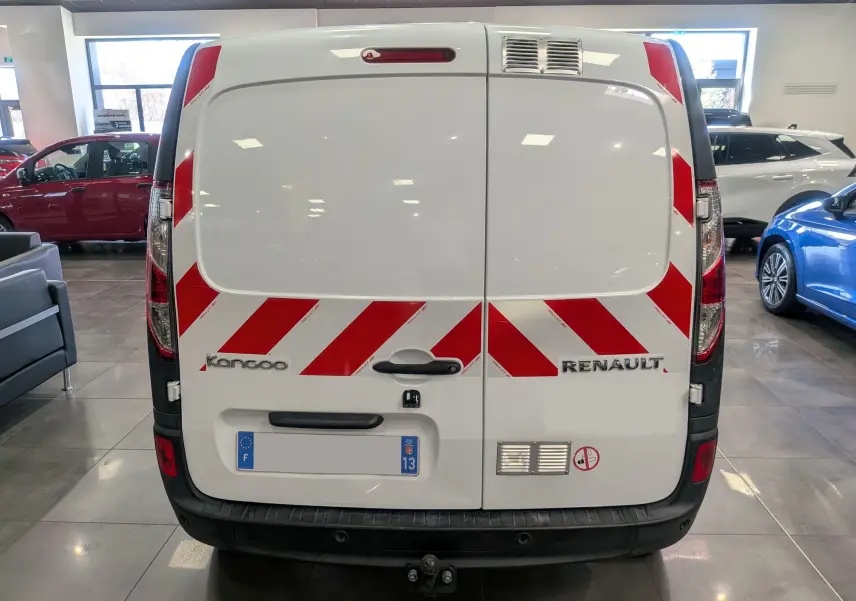 Vue arrière d’un Renault Kangoo Express blanc minéral avec bandes rouges réfléchissantes en diagonale et attelage visible.