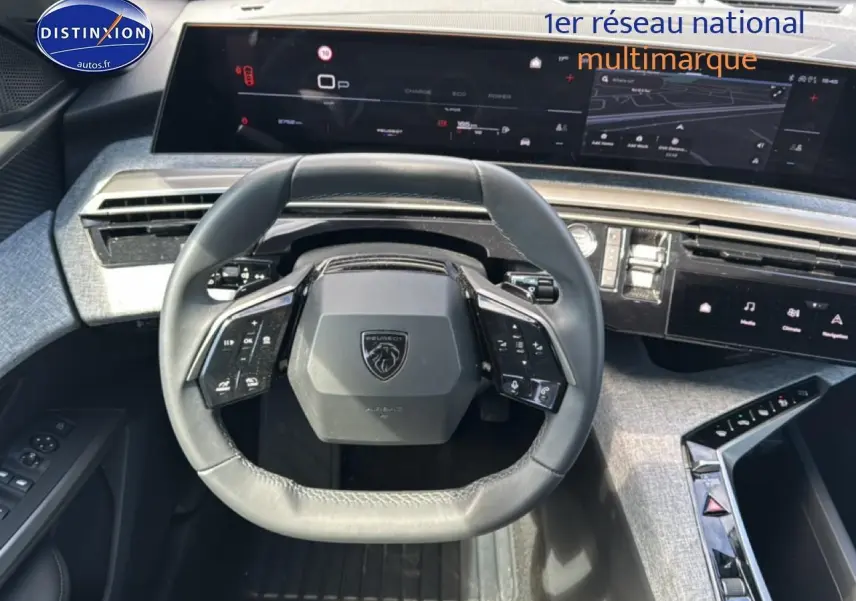 Vue intérieure centrée sur le volant cuir multifonction du Peugeot 5008 Hybrid 145 allure e-dcs6 avec tableau de bord numérique.