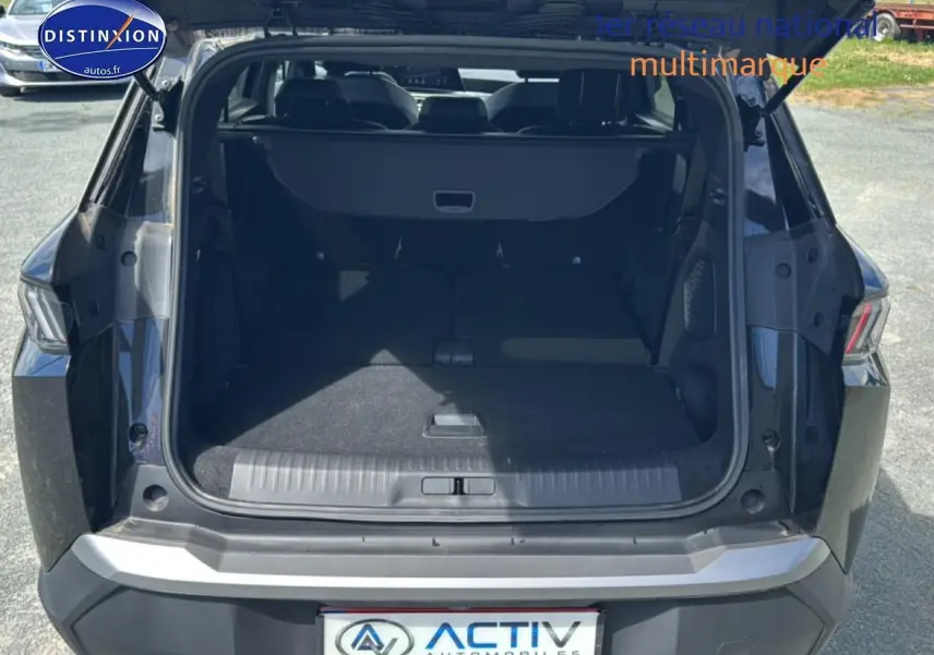 Coffre ouvert vu de l'arrière d'un Peugeot 5008 Hybrid 145 allure noir, montrant l'espace de chargement et la banquette arrière.
