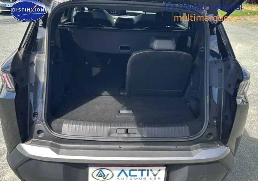 Coffre ouvert vue arrière d’un Peugeot 5008 noir avec banquette arrière partiellement rabattue.