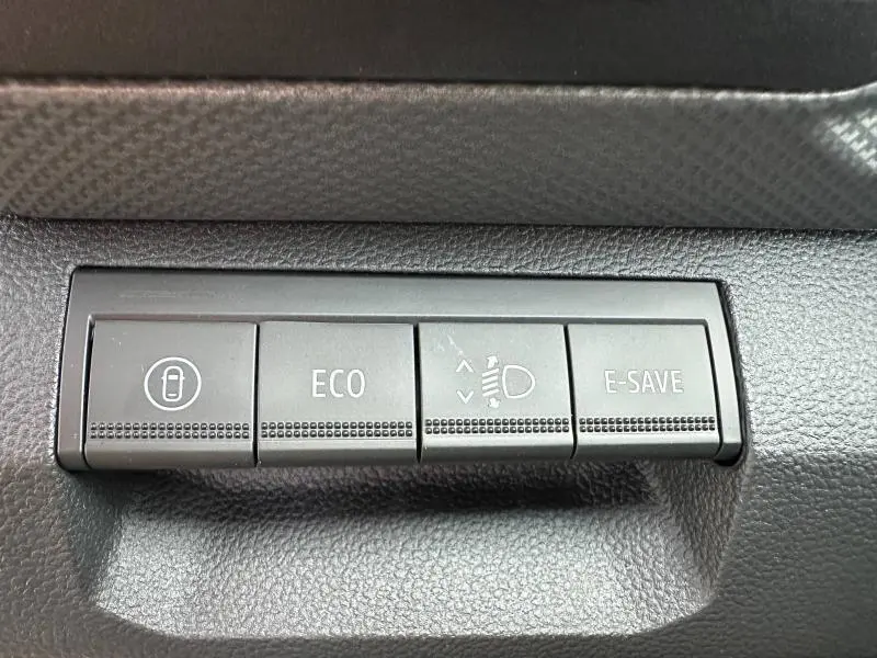 Gros plan sur les boutons de commande noirs du tableau de bord du Dacia Duster 2025, avec fonctions ECO et E-SAVE visibles.