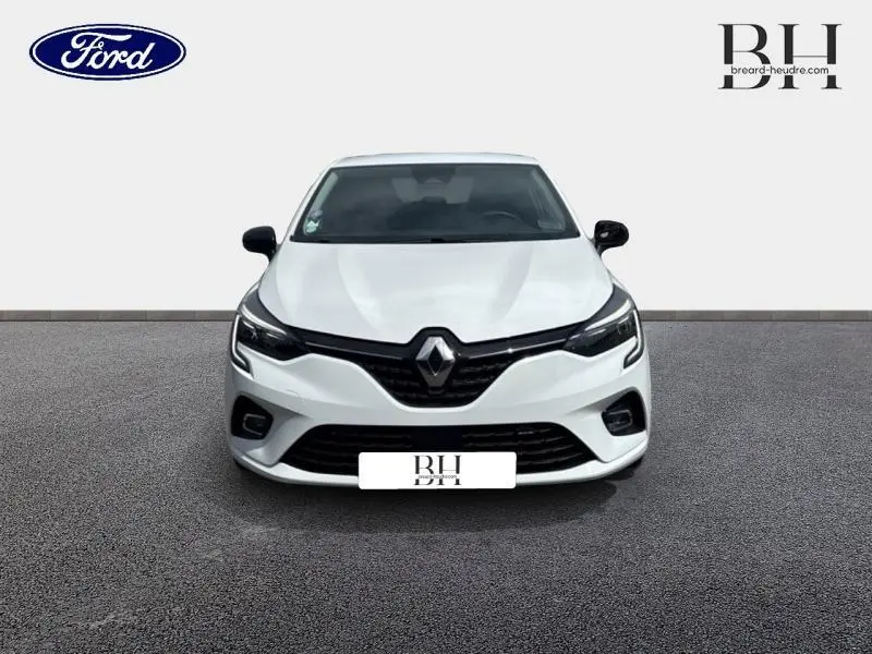 Vue avant d'une Renault Clio blanche 2023 avec calandre noire et phares LED distinctifs.