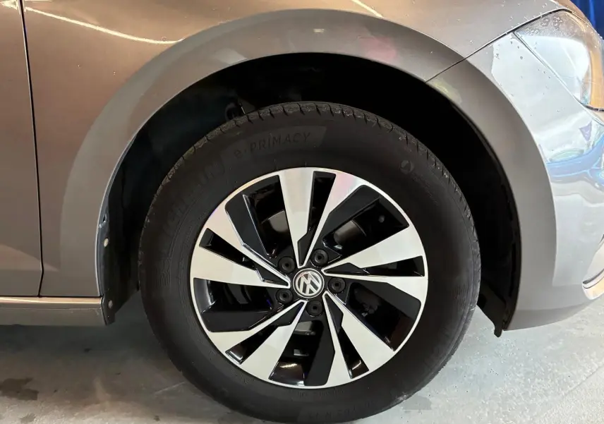 Gros plan sur la roue avant gauche d'une Volkswagen Polo gris métallisé avec jante alliage bicolore moderne.