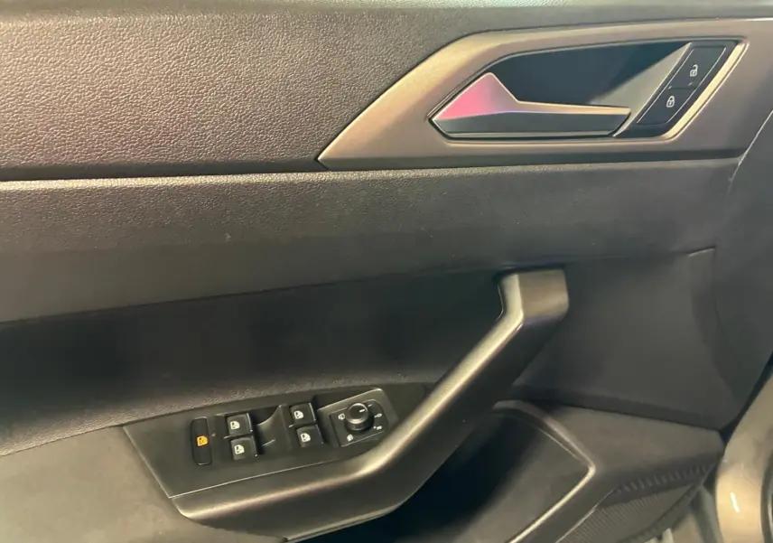 Vue rapprochée de la porte intérieure côté conducteur d'une Volkswagen Polo 2018, avec commandes de vitres et verrouillage.