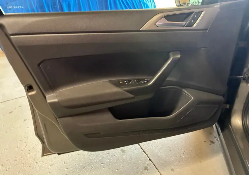 Vue intérieure du panneau de porte avant gauche gris foncé de la Volkswagen Polo 1.0 TSI 95 Confortline 2018 avec commandes électriques.