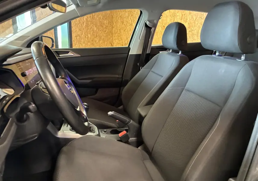 Vue intérieure côté conducteur de la Volkswagen Polo gris 2018, sièges tissu noir et volant multifonction.
