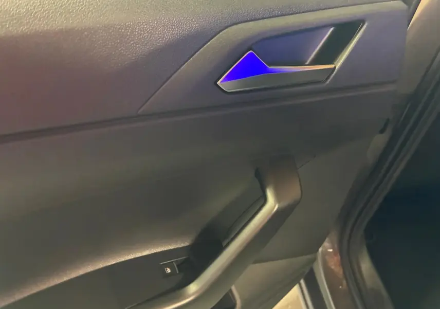 Vue rapprochée de la porte avant gauche de la Volkswagen Polo gris, montrant la poignée intérieure et le bouton de verrouillage.