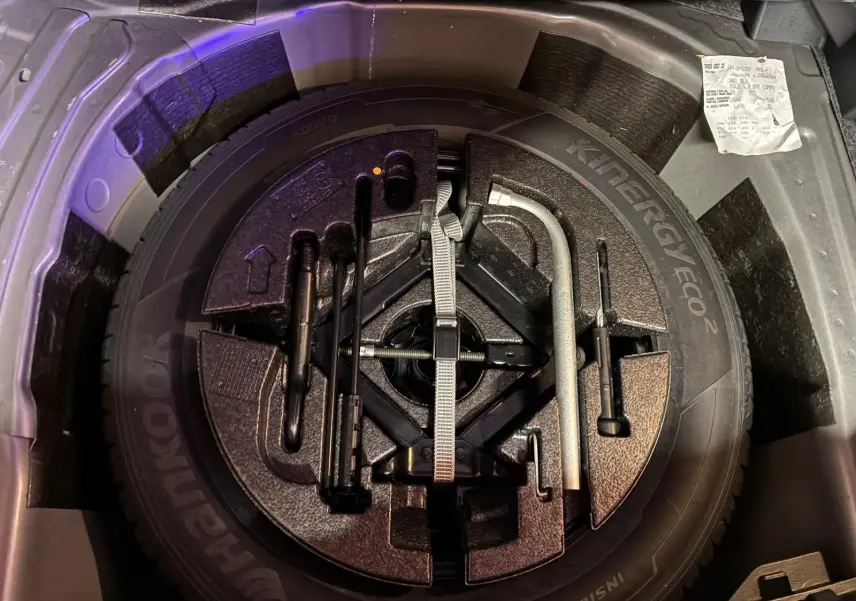 Vue plongeante sur la roue de secours et les outils de bord dans le coffre d'une Volkswagen Polo gris 2018.