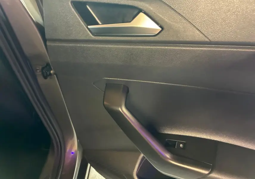 Détail de la porte intérieure côté gauche d’une Volkswagen Polo gris 2018, avec poignée noire et bouton de verrouillage.