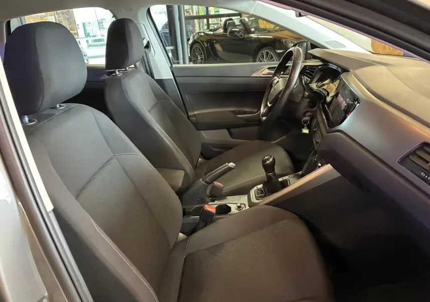 Vue intérieure côté conducteur de la Volkswagen Polo gris 2018, montrant les sièges tissu noirs et la boîte manuelle.