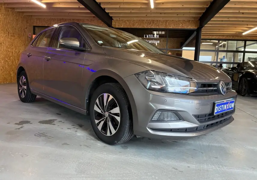 Volkswagen Polo gris 1.0 TSI 95 Confortline vue 3/4 avant droit dans un garage avec éclairage intérieur.