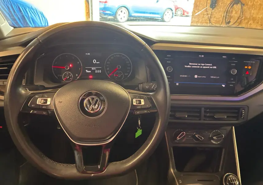 Vue de face de l’intérieur noir d’une Volkswagen Polo 2018, volant multifonctions et écran tactile central allumé.