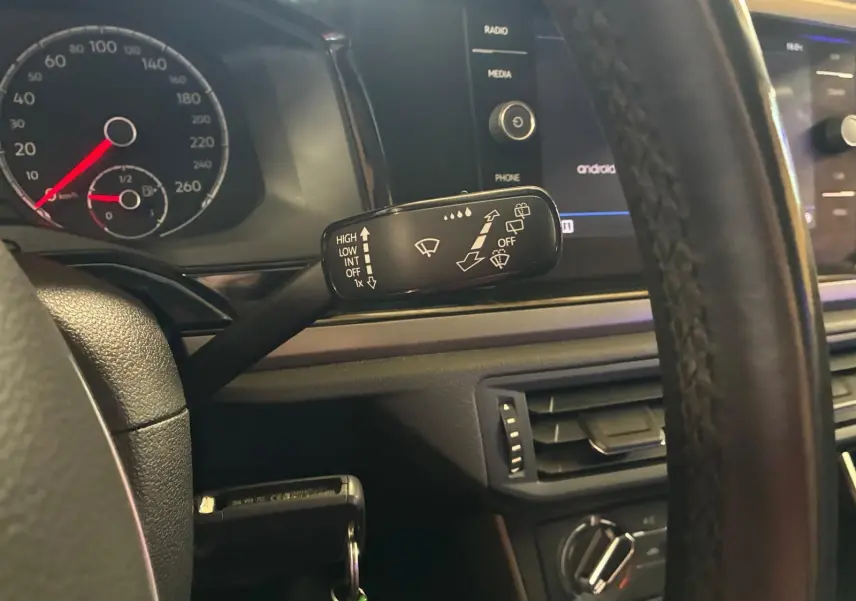 Vue intérieure du volant et du commodo d’essuie-glace d’une Volkswagen Polo gris 2018 avec tableau de bord et écran tactile.