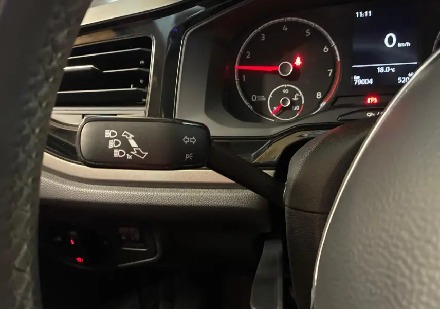 Vue rapprochée du commodo gauche et du tableau de bord noir d'une Volkswagen Polo gris, affichant le compte-tours et l'écran digital.