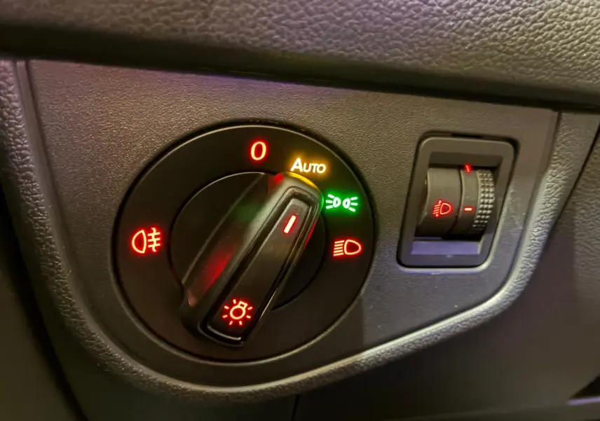 Gros plan sur le bouton de commande des phares avec réglage automatique, sur tableau de bord noir d'une Volkswagen Polo gris 2018.