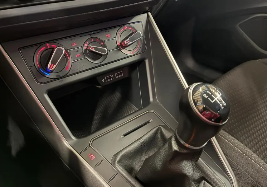 Vue rapprochée de la console centrale d’une Volkswagen Polo 1.0 TSI 95 Confortline 2018, avec levier de vitesse manuel et commandes de climatisation.
