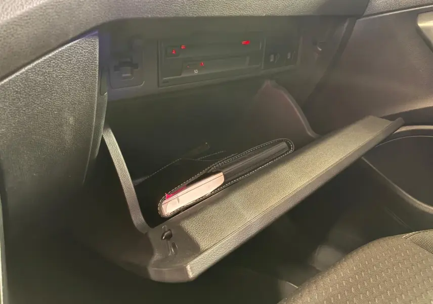 Gros plan de la boîte à gants ouverte de la Volkswagen Polo 1.0 TSI 95 Confortline, intérieur tissu noir.