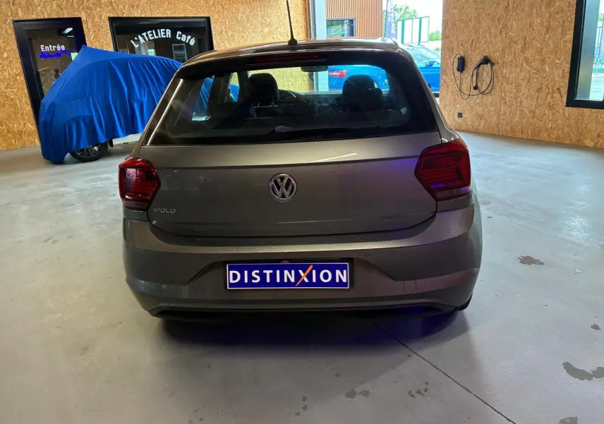 Vue arrière d'une Volkswagen Polo gris métallisé 2018, avec feux arrière rouges et cinq portes, stationnée en intérieur.