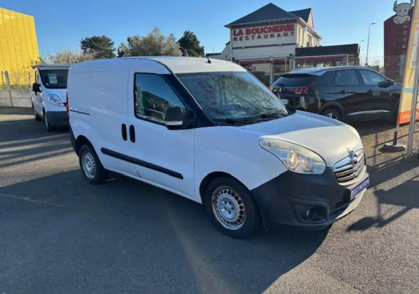 Vue 3/4 avant droite d’un Opel Combo blanc avec jantes tôle et pare-chocs noirs, stationné en extérieur.