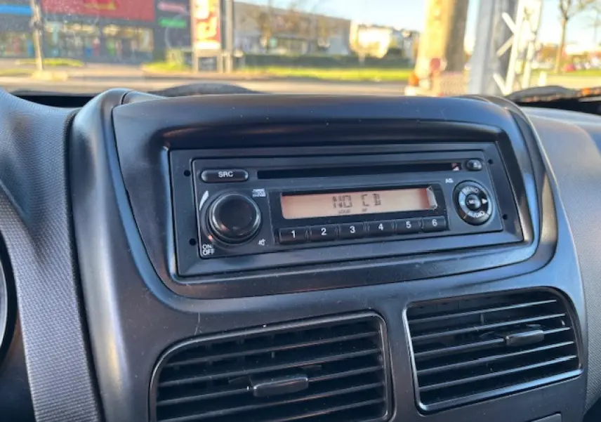 Gros plan sur la radio CD intégrée au tableau de bord noir de l’Opel Combo blanc, version L1H1 2015.