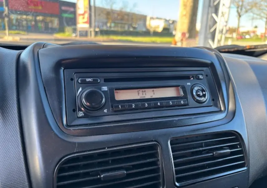 Vue rapprochée de la radio CD noire intégrée au tableau de bord du Opel Combo blanc de 2015.