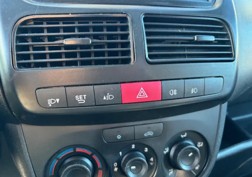 Détail de la console centrale de l’Opel Combo blanc 2015, montrant les commandes de climatisation et les boutons de sécurité.