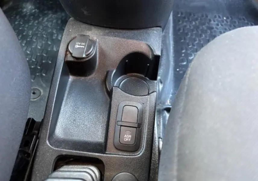 Détail de la console centrale noire de l'Opel Combo L1H1 2015 avec bouton ASR off et prise 12V visible entre les sièges.