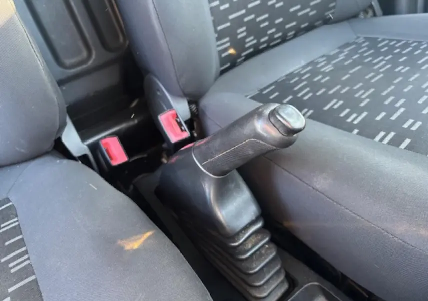 Gros plan sur le levier de frein à main entre les sièges avant gris de l’Opel Combo blanc L1H1 2015.
