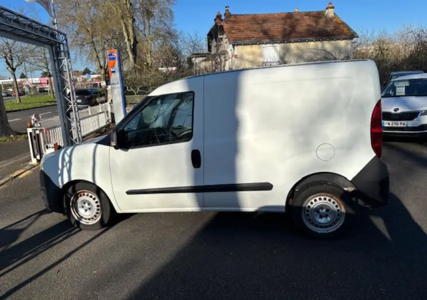 Vue de profil côté gauche d’un Opel Combo blanc avec jantes tôle 15 pouces et porte latérale coulissante tôlée.