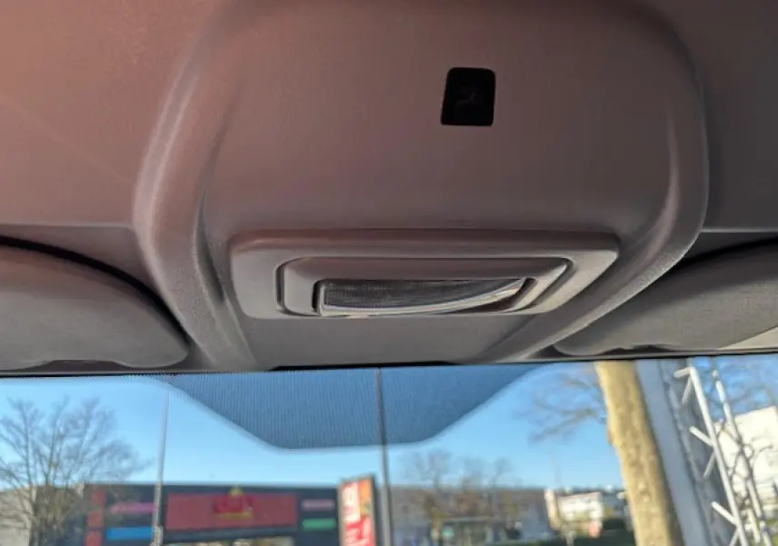 Vue intérieure du plafonnier gris clair de l’Opel Combo blanc, avec pare-brise et paysage urbain en arrière-plan.