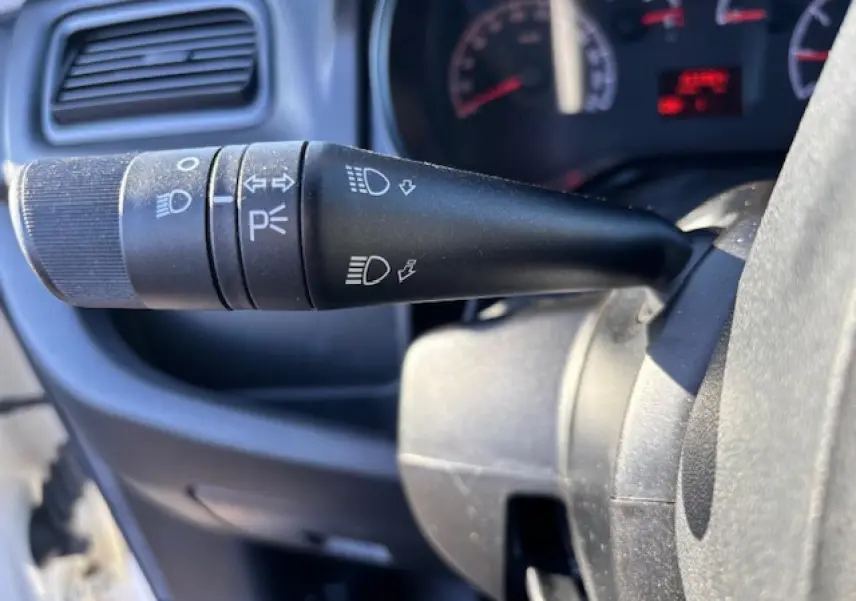 Gros plan sur la manette des feux et clignotants à gauche du volant dans l’habitacle du fourgon blanc Opel Combo L1H1.