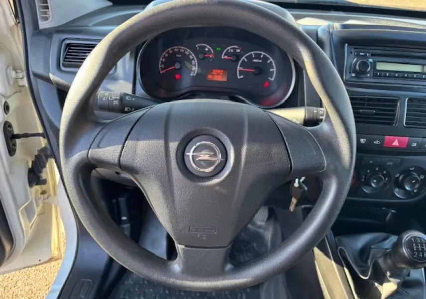 Vue intérieure centrée sur le volant Opel noir, tableau de bord et levier de vitesse d’un Combo blanc de 2015.