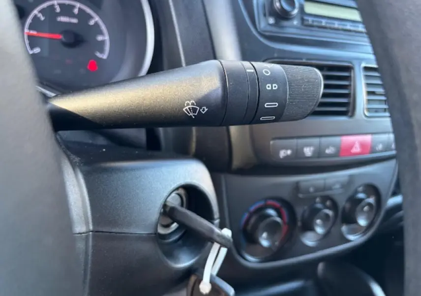 Gros plan sur le commodo gauche et le tableau de bord noir de l'Opel Combo L1H1 2015 avec clés dans le contacteur.