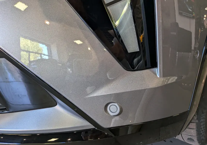 Gros plan sur le pare-chocs avant gris schiste du Renault Rafale, mettant en valeur le capteur de stationnement et le feu LED.