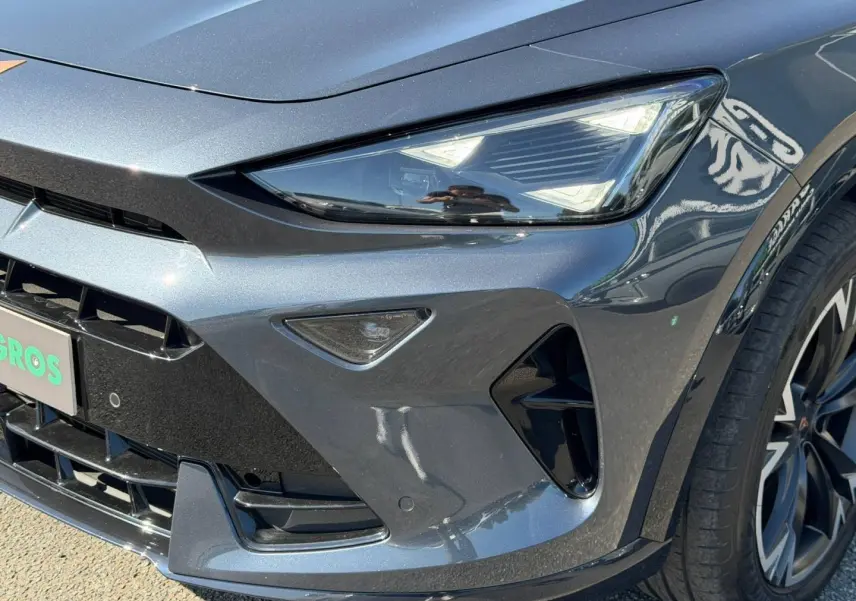 Gros plan sur l'avant droit du CUPRA Formentor gris magnétique métallisé, mettant en valeur le phare LED et la calandre sportive.