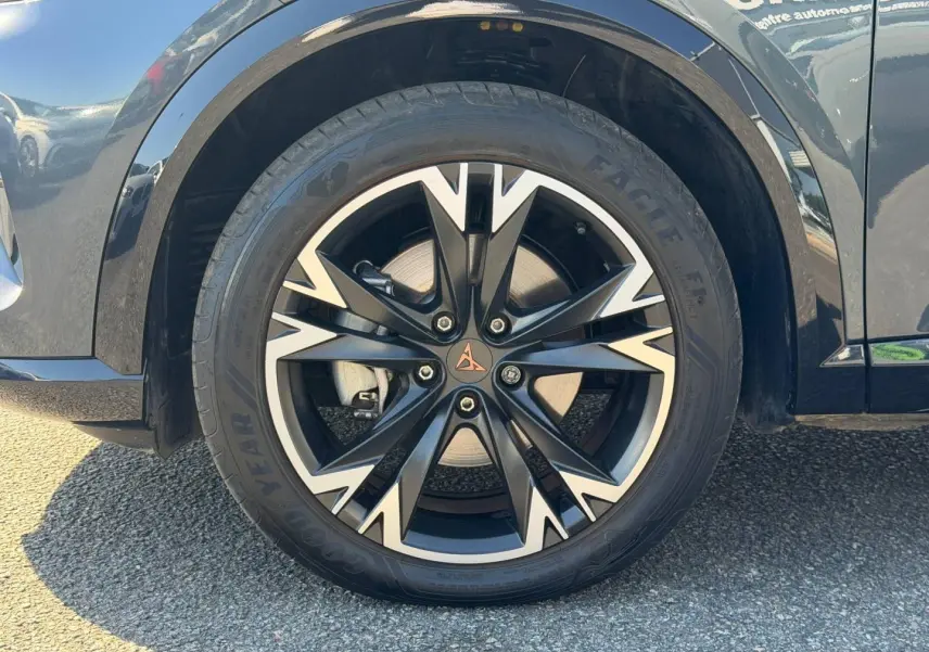 Gros plan sur la jante alu noire et argentée avec logo CUPRA, montée sur un pneu Goodyear, côté avant droit du Formentor gris métallisé.